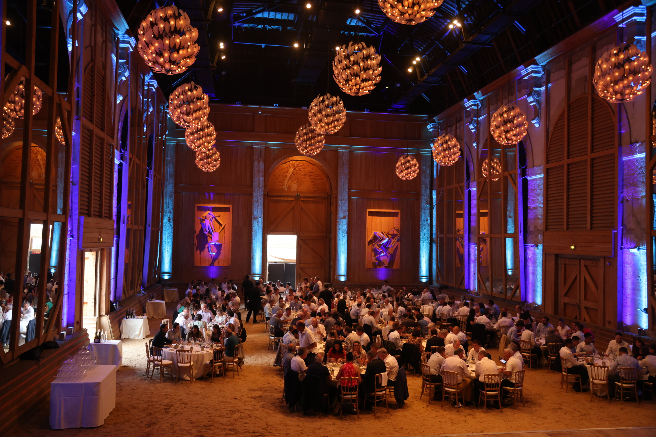 Manège de l'Académie Équestre de Versailles - format dîner de gala pour 320 personnes avec tables dressées et lumières rose